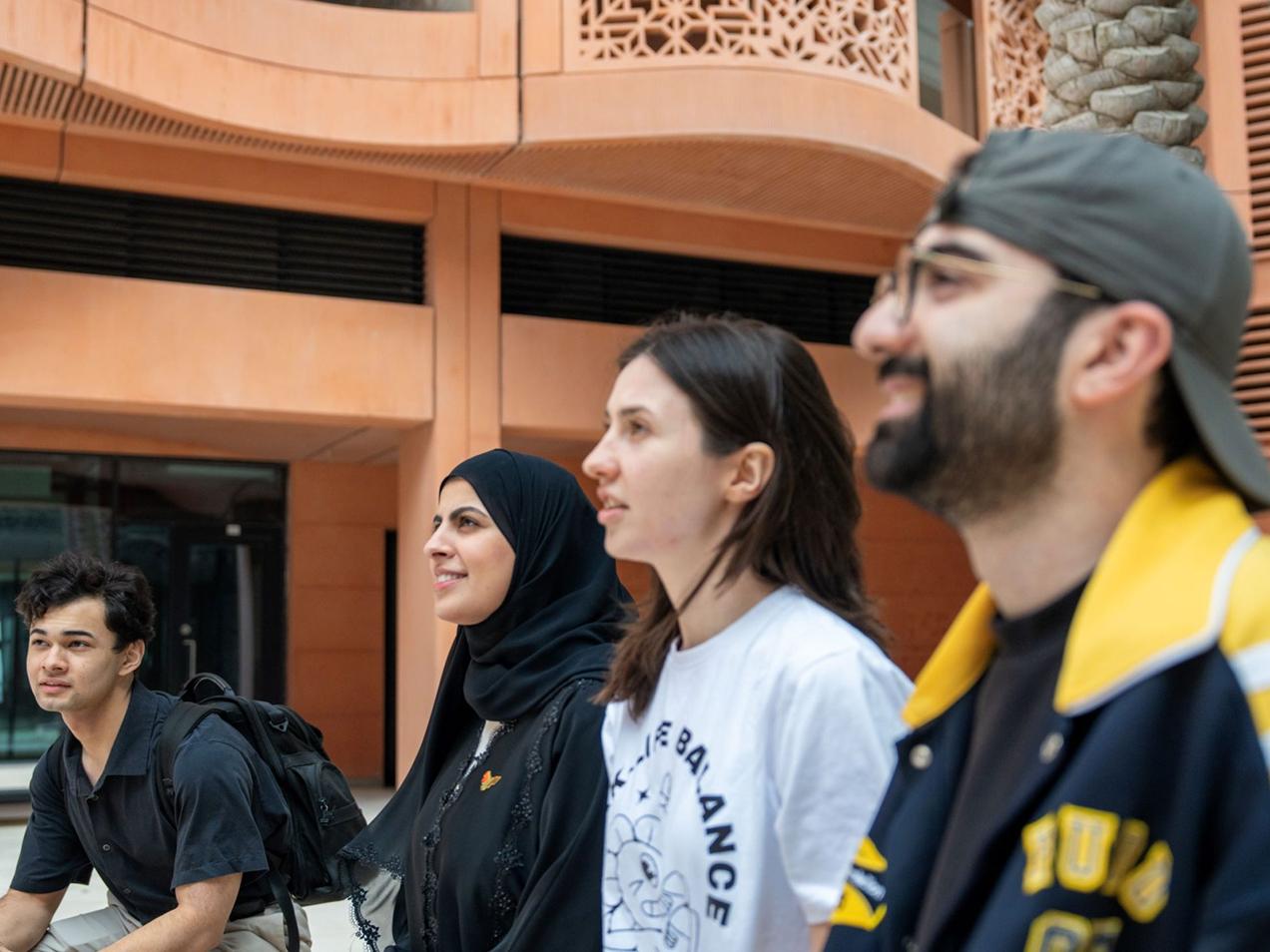 Claude responded: A group of diverse students standing together outside on the MBZUAI campus.A group of diverse students standing together outside on the MBZUAI campus.